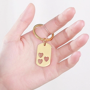 Macro shot of gold stainless steel keychain with three hollow heart cutouts on a metal tag