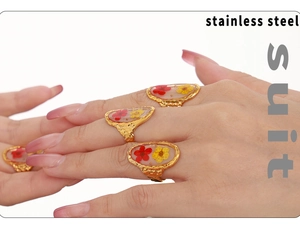 Detail of stainless steel gold ring set with colorful resin dried flowers on hand
