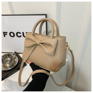 Close-up of beige bow handbag with matte PU texture and elegant curved top handles