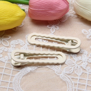 Close-up of wavy cream-colored metal hair clips on a decorative floral lace background