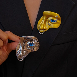 Gros plan de la broche visage surréaliste avec œil bleu et anneau de nez sur un blazer