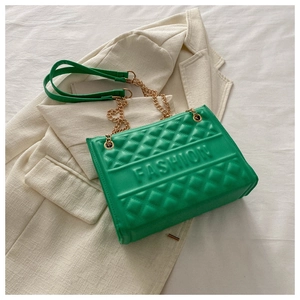 Detail of green quilted crossbody bag with embossed lettering and gold chain strap