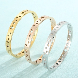Three stacked bangles in gold, rose gold, and silver with hollow star-shaped cutouts