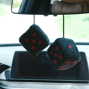 Detail view of plush navy car dice with red heart patterns hanging on a rearview mirror