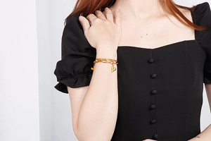 Close-up of double-layer gold heart bracelet worn on wrist with black dress background