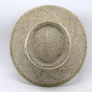 Close-up of the woven straw hat with wide brim and elegant light beige decorative ribbon