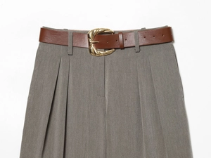 Détail du pantalon gris plissé avec ceinture en similicuir marron et boucle dorée