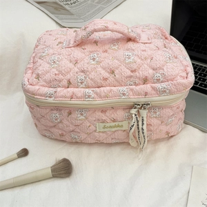 Detail of pink quilted cartoon makeup bag with white rabbit prints and decorative ribbon