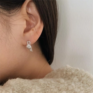 Close-up of a silver knotted stud earring worn by a model in a minimalist lifestyle setting