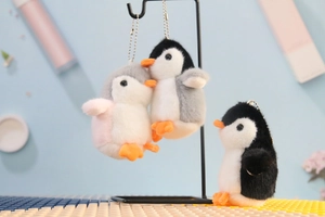 Detailed view of plush penguin keychains in gray and black on a creative display stand
