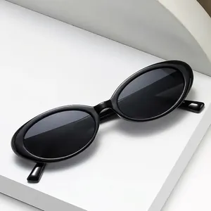 Classic black oval sunglasses with minimalist frame on a modern geometric white stand