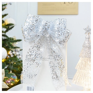 Close-up of sparkling silver sequin Christmas bow topper with festive tree background