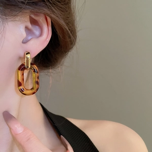 Close-up of a leopard print resin drop earring on a model featuring amber tortoise tones