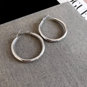 Detailed view of large silver hoop earrings with polished mirror finish on textured fabric