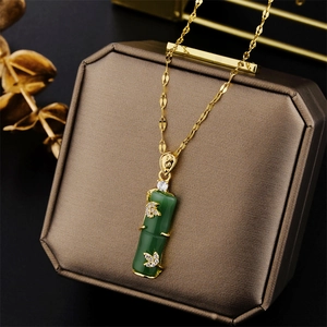 Collana in acciaio titanio dorato con pendente in bambù verde su portagioie marrone