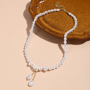 Detail of baroque pearl necklace with white flower charm and golden drop pendants