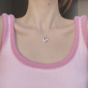 Détail d'un collier avec pendentif cœur ajouré et textures vintage porté par un mannequin
