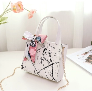 Detail of marble pattern white handbag with pink silk scarf and gold chain strap