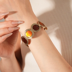 Retro metal cuff bracelet with amber resin round inlays and woven texture on model wrist