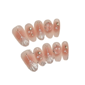 Unghie finte sfumate rosa con perle, catene e glitter luccicanti per un look elegante
