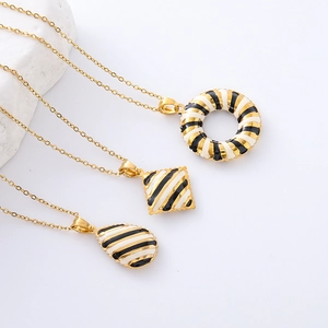 Detailed view of 18K gold plated necklaces with black and white striped geometric pendants