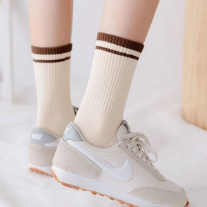 Cream crew socks with brown stripes and ribbed knit texture shown with sneakers