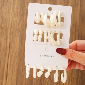 Close-up of white pearlescent resin earring set featuring drop and hoop shapes on card
