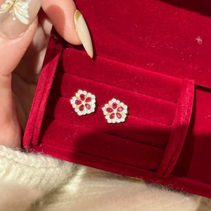 Nahaufnahme von Blumenohrringen mit roten Steinen in einer roten Samtbox aus Gold