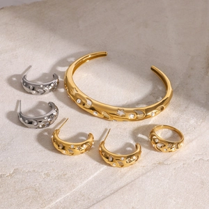 Detailed set of gold celestial star and moon jewelry with rhinestones on stone background