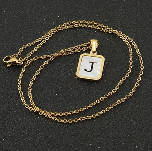 18K gold plated stainless steel necklace with white shell letter J pendant on black background