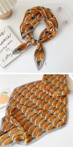 Detail view of orange and grey pleated silk scarf showing scale patterns and styling