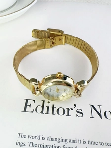Close-up of a vintage gold women's quartz watch with a woven metal mesh strap