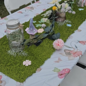 Detail of green faux moss table runner used for forest themed party table decoration