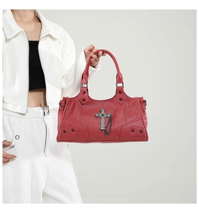 Detail der roten Punk-Handtasche mit Metallkreuz und Kettenhenkel von Model gehalten