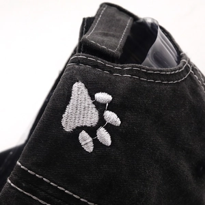 Close-up of white animal paw embroidery on a black washed cotton baseball cap
