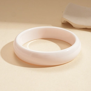 Close-up of pink-white resin bangle with smooth oil luster and warm beige artistic setup