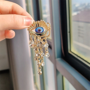 Vintage gold brooch with blue eye design and crystal tassel chains held in hand