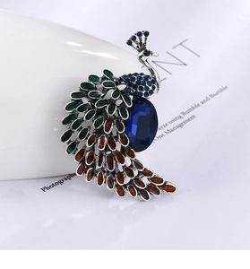 Détail de la broche paon vintage avec strass verts et orange sur alliage d'argent