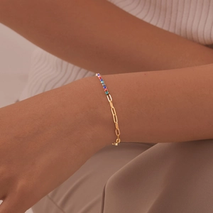 Detail of gold chain bracelet with colorful pavé gemstones on a woman's wrist