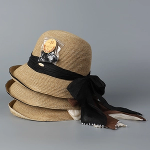 Close-up of woven straw hats with black ribbon bows and pearl details, UPF 50+ protection