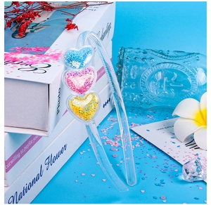 Detail showing transparent plastic headband with colorful glitter-filled heart ornaments