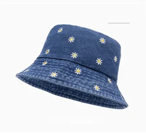 Detailed close-up of white daisy floral embroidery on dark blue denim bucket hat fabric