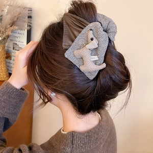 Detail view of a brown plush puppy hair claw clip on a woman's bun hairstyle