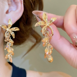 Gros plan de boucles d'oreilles fleur en cristal champagne portées par un mannequin