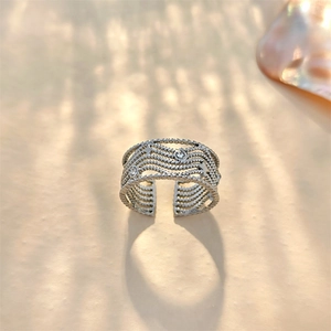 Macro detail of silver multi-layer wavy ring with sparkling inlaid clear gemstones