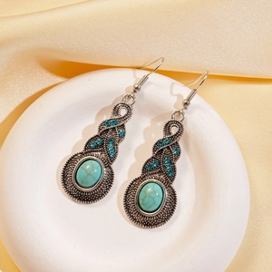 Close-up of vintage silver earrings with blue turquoise and rhinestones on silk