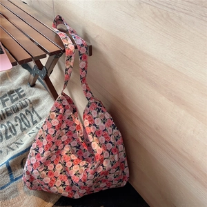 Detailed view of floral cotton tote bag with pink rose patterns on light wood background