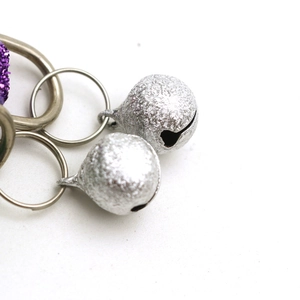 Close-up of glitter purple pet collar featuring two silver metallic bells on a white backdrop