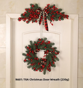 Close-up of artificial pine needles with red berries and a red plaid fabric bow tie