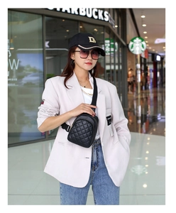Model wearing a black quilted waist bag with adjustable strap in a modern mall setting